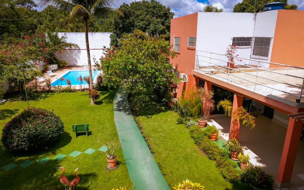 Jardim da clínica, com gramado, caminho, canteiros e a varanda do prédio ao fundo