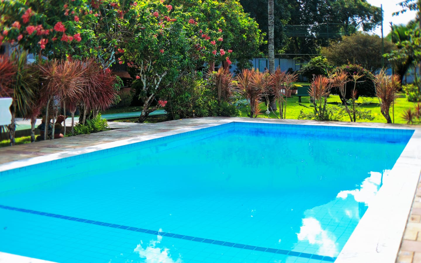 Piscina da clínica, com área de convívio e vegetação ao redor