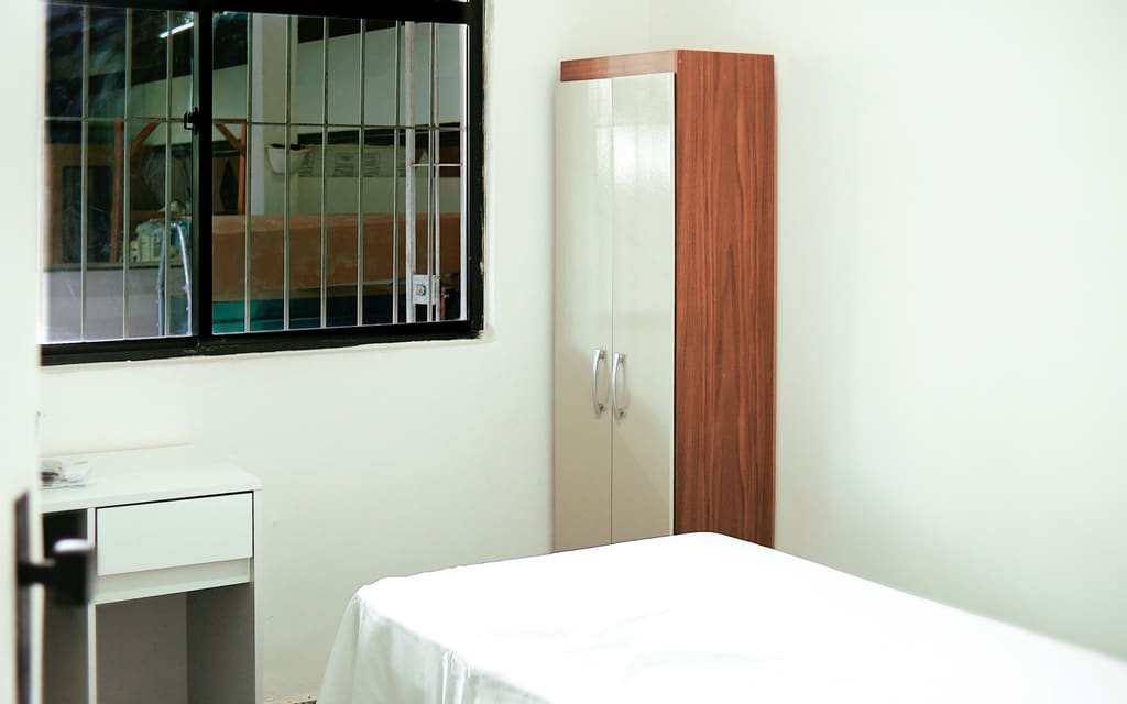 Quarto da clínica, com cama, armário e escrivaninha